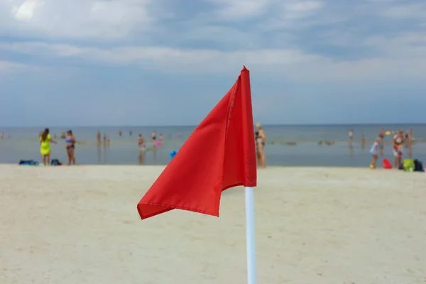 Drapeau rouge sur une plage de sable — Photo