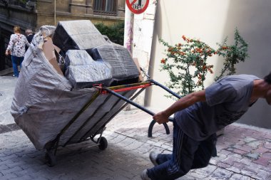 Istanbul'da sokakta bir sepeti kutuları ile Porter sürükler