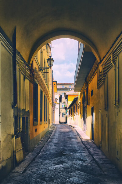Arch on the old narrow street with yellow facades and street lights in a typical small Italian town