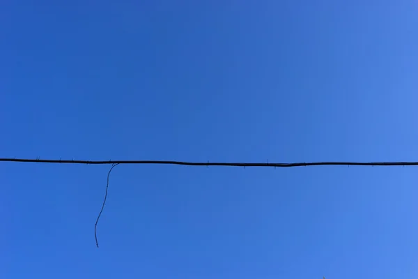 The black wire on a background of blue sky — Stock Photo, Image