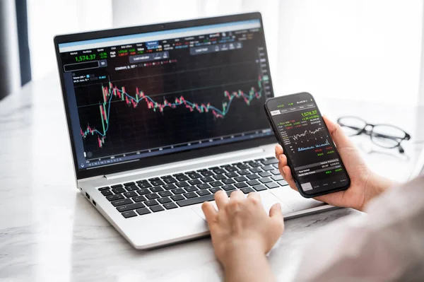 Hand Holding Smartphone Stock Market Data Using Laptop Display Graph — Stock Photo, Image