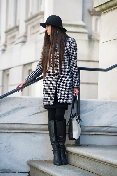 Elegante y de moda joven empresaria de pie al aire libre sosteniendo una bolsa con gato y sombrero negro —  Fotos de Stock