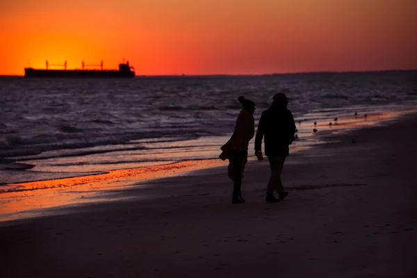 日落时分在海洋海滩上散步的夫妇剪影 — 图库照片