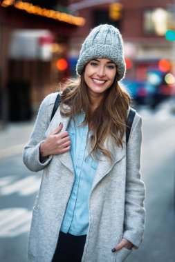 Beautiful smiling woman walking on the New York City street wearing casual style clothes