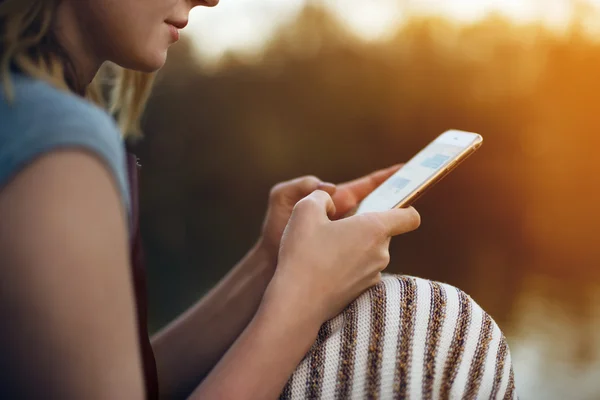 Lány textil mobiltelefon kint ül napnyugta időpontja — Stock Fotó