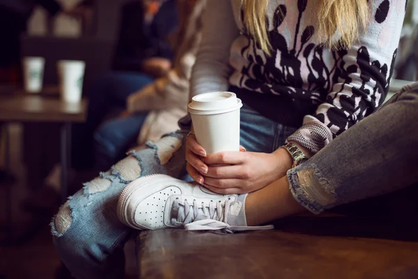 Donna mani tenendo tazza di caffè di carta mentre seduto in caffetteria — Foto Stock