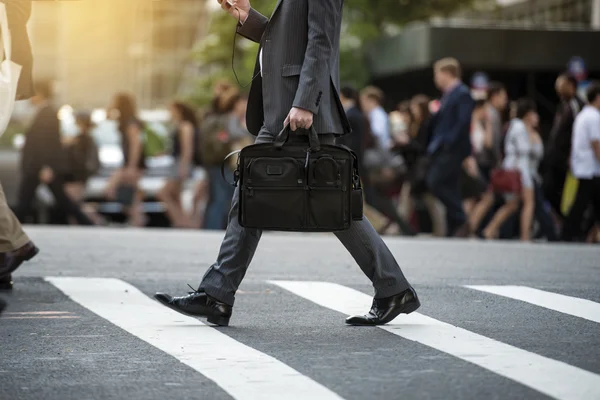 Empresário atravessando a rua na passadeira e honrando uma bolsa de laptop e smatphone na cidade Fotos De Bancos De Imagens