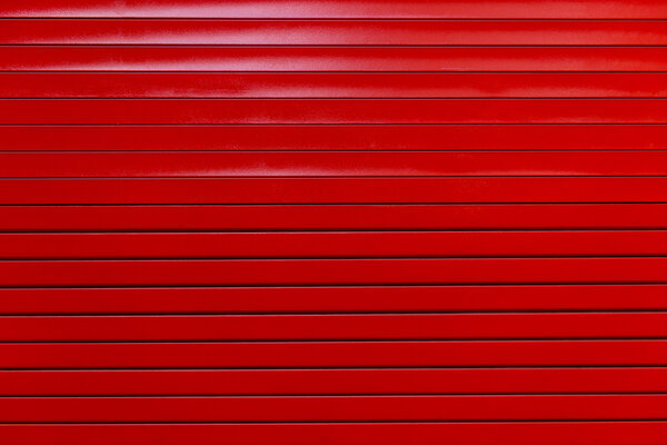 Red painted metal garage door or wall. Red garage door with black stripes. Black and red metal wall background.