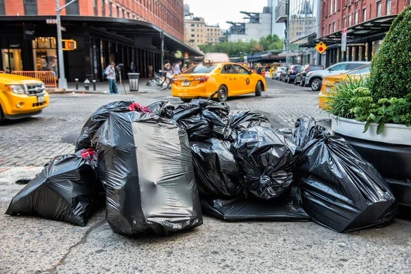 Sacos pretos de lixo na calçada na rua de Nova York à espera de caminhão de lixo de serviço. Lixo embalado em sacos de lixo grande pronto para o transporte . — Fotografia de Stock