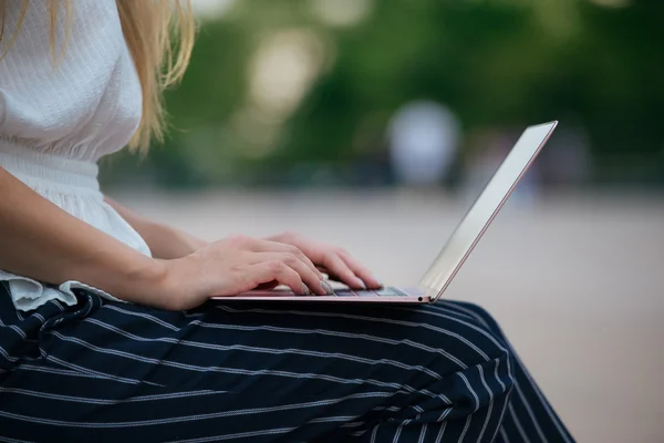 Oturma ve açık havada çalışan dizüstü klavyede yazarak işkadını. Kadın iş kıyafeti Internet üzerinde serbest iş yapıyor. El yazma. — Stok fotoğraf
