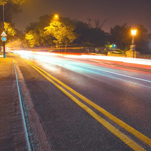 Route asphaltée de nuit dans la ville avec des sentiers de lumière de voiture — Photo