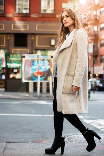 Joven mujer hermosa adulta caminando por la calle de la ciudad vistiendo ropa casual de otoño de estilo callejero con chaqueta gris y vaqueros negros — Foto de Stock