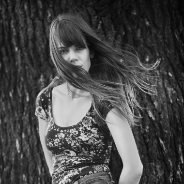 Bir ağaç rüzgarlı saçlı yakınındaki poz kadın fotoğrafı siyah-beyaz