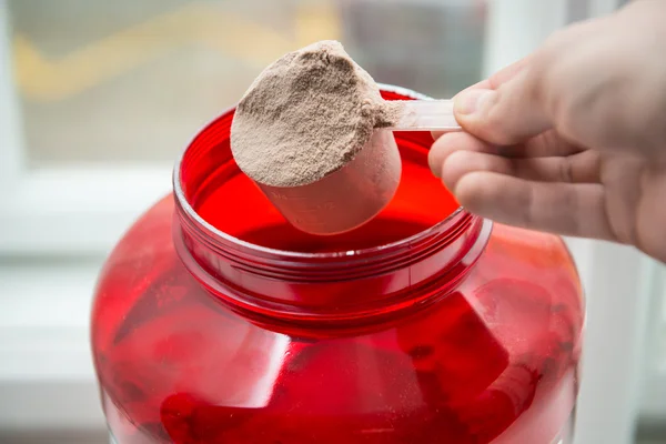 Man taking protein from container by the scoop — Stock Photo, Image