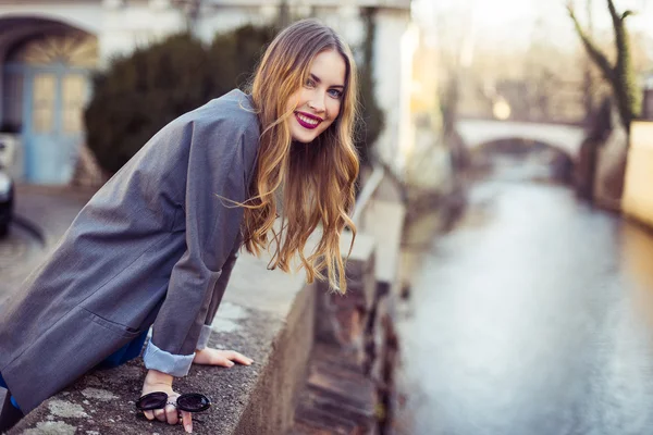 Hermosa mujer sonriente caminando en la ciudad cerca del terraplén del río —  Fotos de Stock