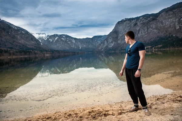 Strong man standing and relaxing near mountain lake — Stock Photo, Image