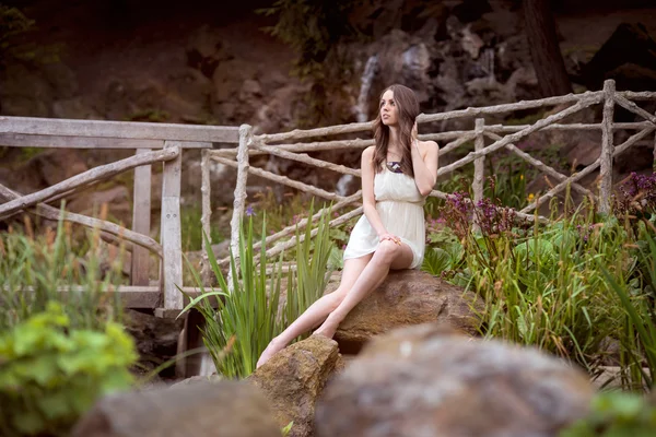 Beautiful woman in white dress sitting at nature — Stock Photo, Image