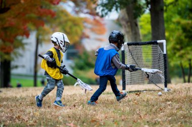 Sonbahar parkta onun sopayla lacrosse oynayan küçük çocuk.