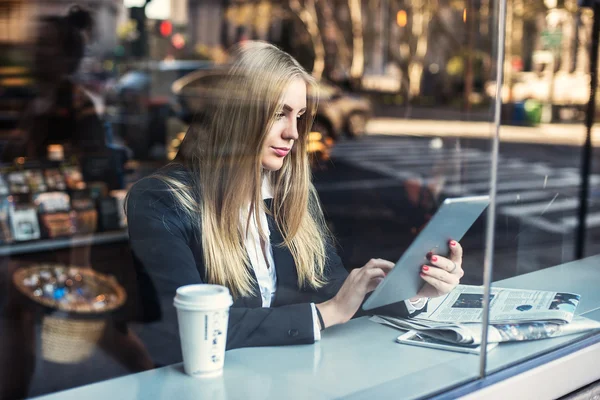 Affärskvinna sitter i café och använda TabletPC och dricka kaffe. Stockbild