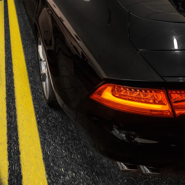 Чорний швидкісний автомобіль на асфальтній дорозі з двома жовтими лініями розмітки — стокове фото