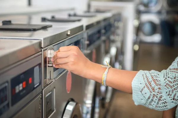 Woman making payment putting quarter to washing laundromat machine in the public laundry — Stock Photo, Image