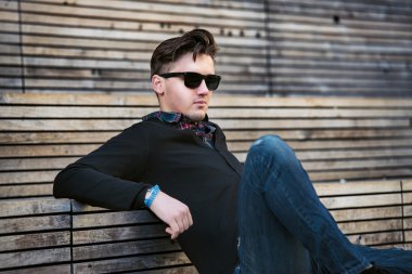 Açık havada ahşap merdivenlerde oturan yakışıklı moda adam