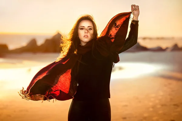 Beautiful fashion woman posing on the ocean beach wearing autumn clothes at sunset time — Stock Photo, Image