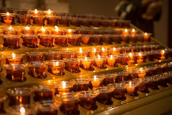 Velas de oração iluminam a escuridão em uma igreja — Fotografia de Stock