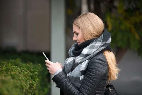 Beautiful blonde woman walking and texting on cell phone — Stock Photo, Image