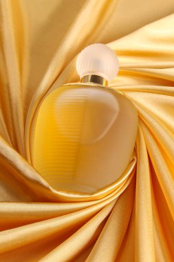 Altın sarısı ipek üzerinde parfüm şişesi katlanmış kumaş arka plan parfüm şişesi koyu boş arka planda. Üst görünüm. 
