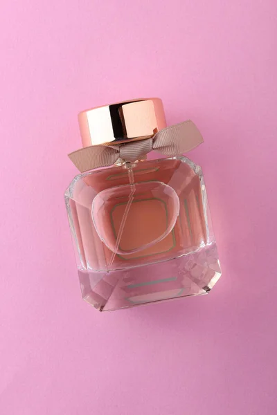 Açık pembe arka planda parfüm şişeleri ve çiçeklerle düz kompozisyon, metin için boşluk