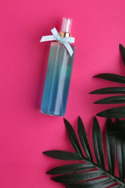 Plastik yüz nemlendirici, saç spreyi veya vücut sisi ve pastel pembe arka planda izole edilmiş yeşil bitkisel yapraklar, deri döşeme, üst manzara, fotokopi alanı, doğal organik güzellik ürünü.