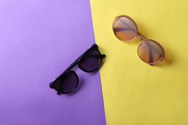Stylish fashionable round sunglasses on pink blue paper background. Top view. Minimalism