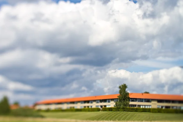 Maison avec prairie sous un ciel nuageux — Photo