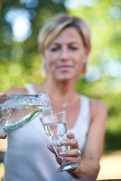 Donna versando acqua in un bicchiere — Foto Stock