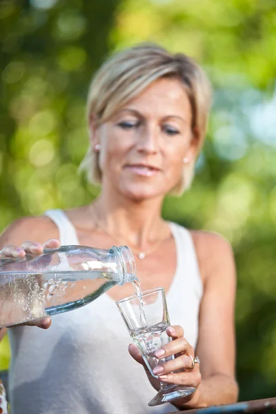 Woman pouring water in a glass — Stock Photo, Image