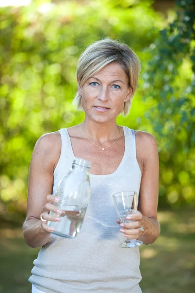 Kobieta, wlewając wodę w szklance — Zdjęcie stockowe