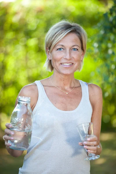 Donna versando acqua in un bicchiere — Foto Stock