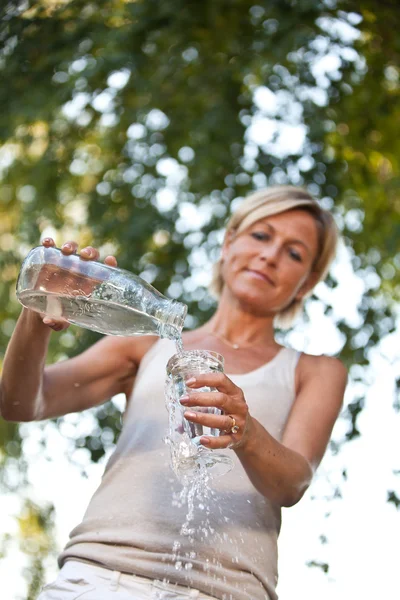 Mujer vertiendo agua en un vaso —  Fotos de Stock