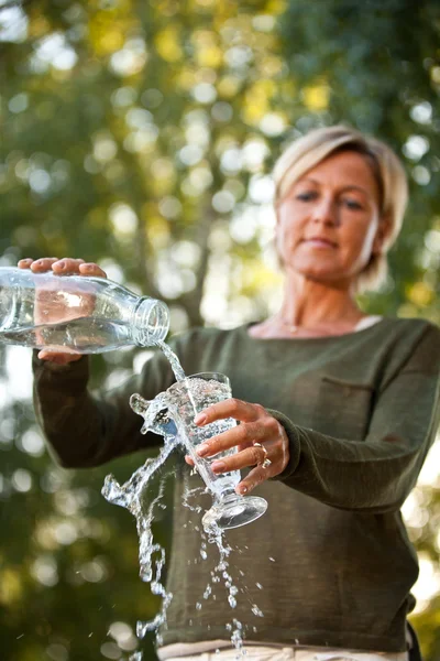 Woman pouring water in a glass — Stock Photo, Image