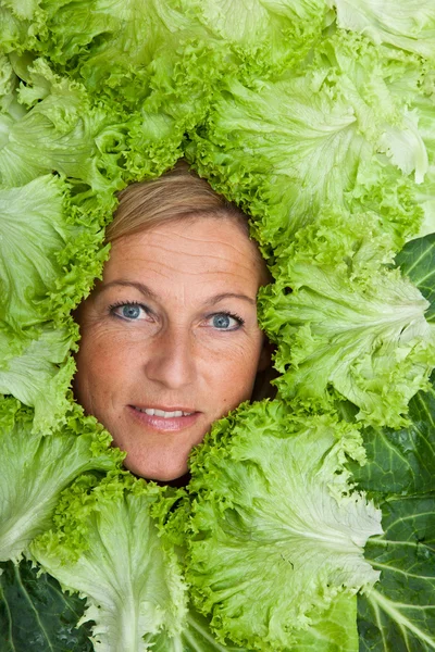 Nő saláta levelek rendezett körül az arcát — Stock Fotó
