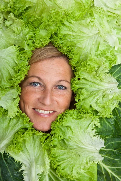 Nő saláta levelek rendezett körül az arcát — Stock Fotó