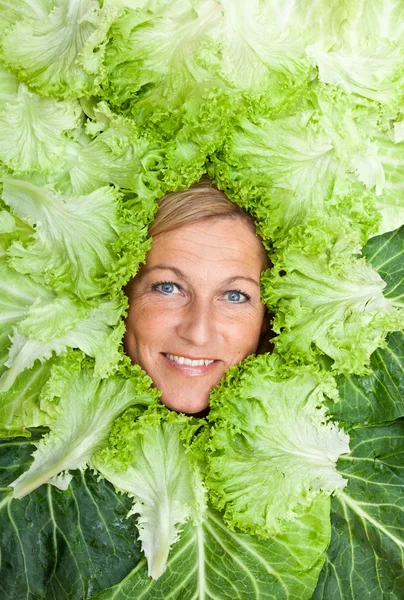 Femme avec des feuilles de salade disposées autour de son visage — Photo