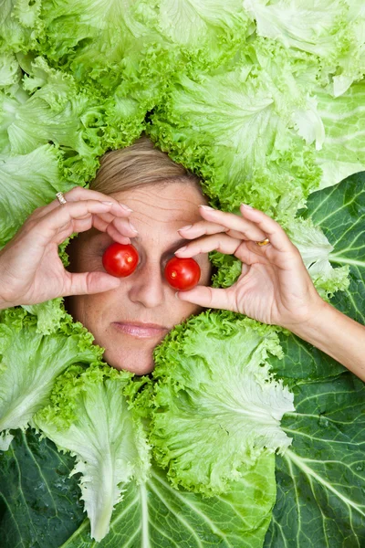 Frau mit Salatblättern um ihr Gesicht angeordnet — Stockfoto