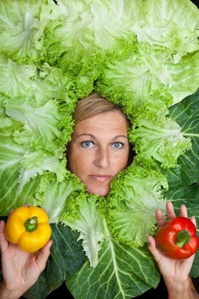 Frau mit Salatblättern um ihr Gesicht angeordnet — Stockfoto