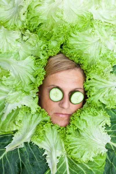 Vrouw met salade verlaat gearrangeerde rond haar gezicht — Stockfoto