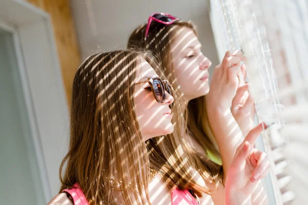 Two beautiful blond teenage girls having fun spying of window — Stok fotoğraf