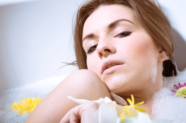 Schöne sexy junge Frau mit Bad mit Blütenblättern — Stockfoto