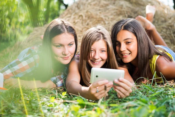 Three happy young girlfriends doing selfie by phone — Stock Photo, Image