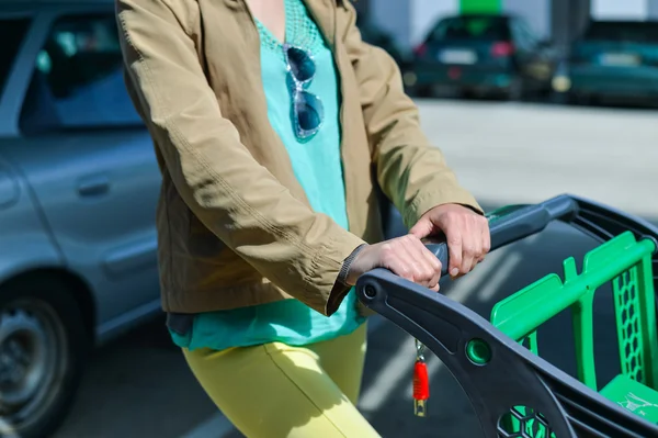 Mulher com carrinho de compras no estacionamento — Fotografia de Stock